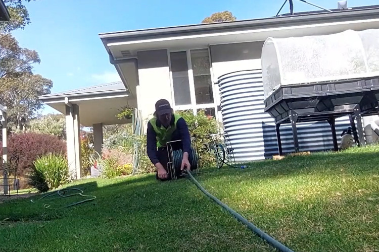 
The wollongong downpipe cleaner is putting away his hose, signaling the end of his workday.